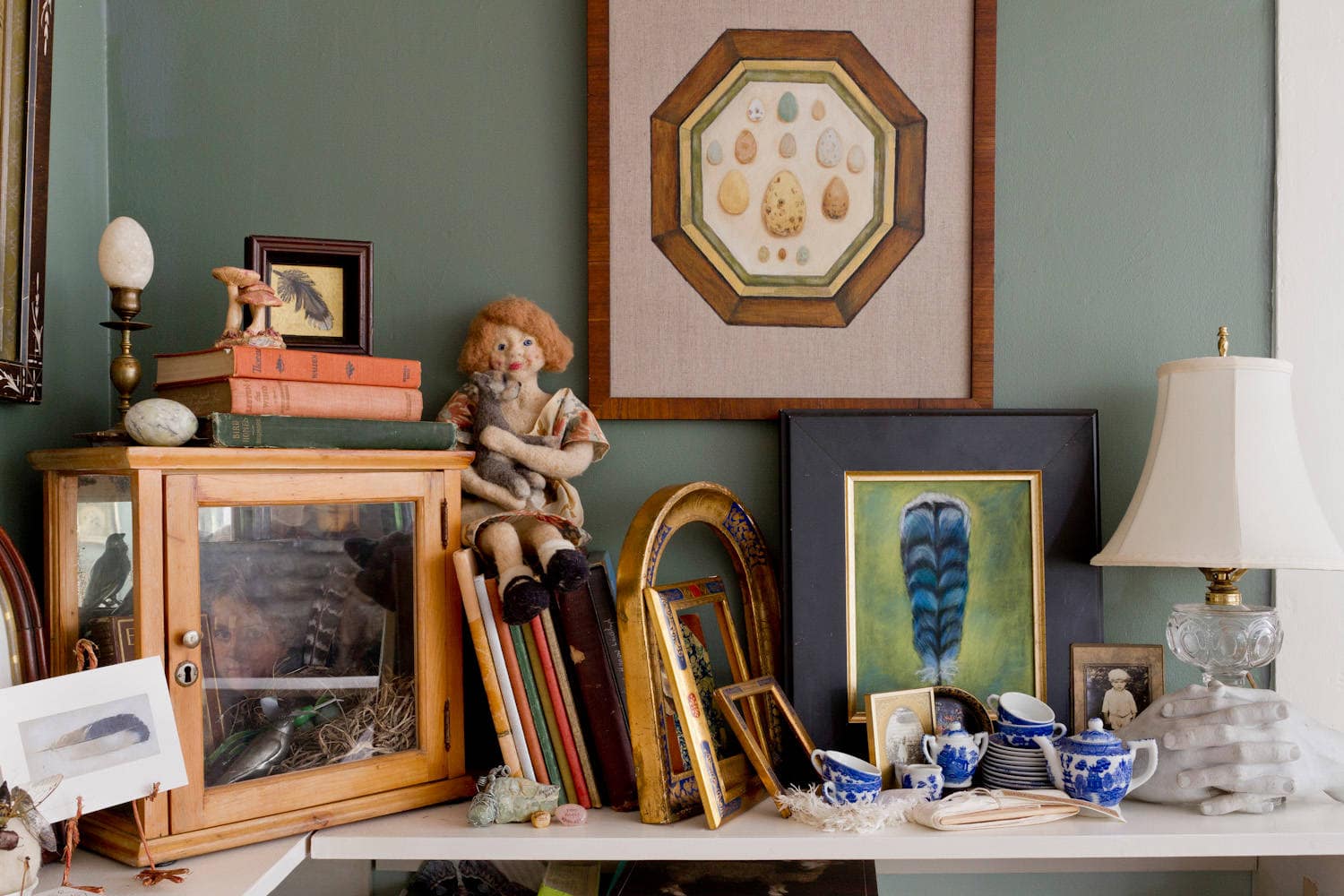 Cottage living room featured in home tour, showing a corner bookshelf with books and figurines.