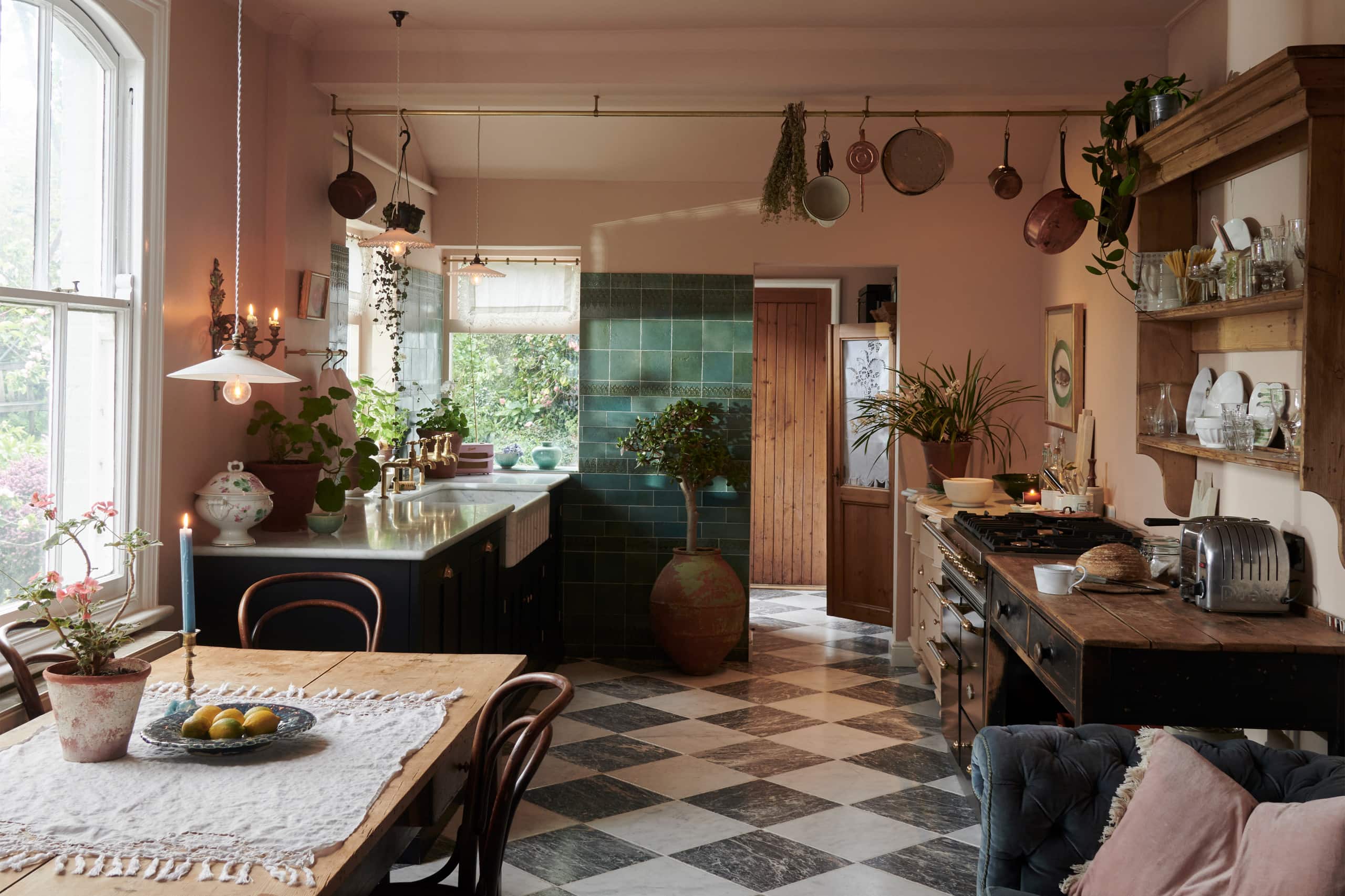 cottage-inspired kitchen featuring green esmerald kitchen tiles, pink walls and white and black checkerboard flooring.