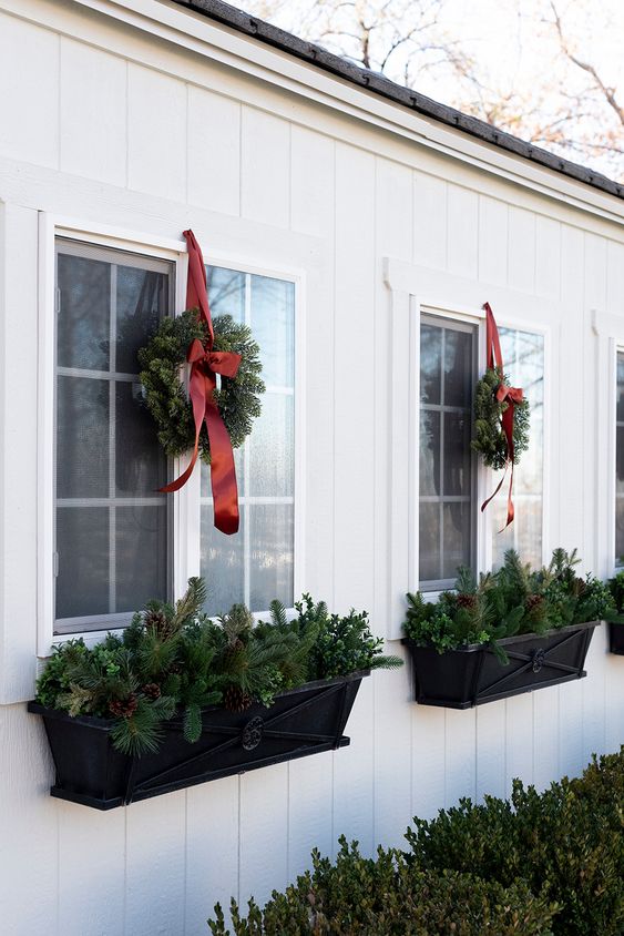  outdoor decorating ideas featuring white exteriors, windows ans wreaths on each window with planters