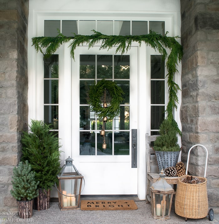 Front white door featuring green garland  outdoor decorating ideas