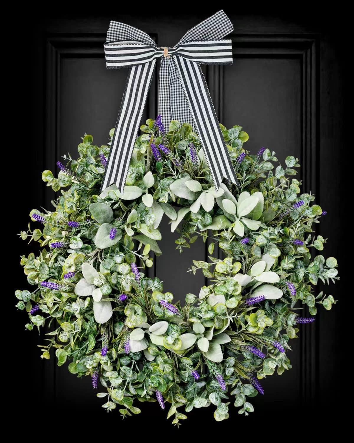 elegant wreath idea against a black front door with white and black stripped ribbon