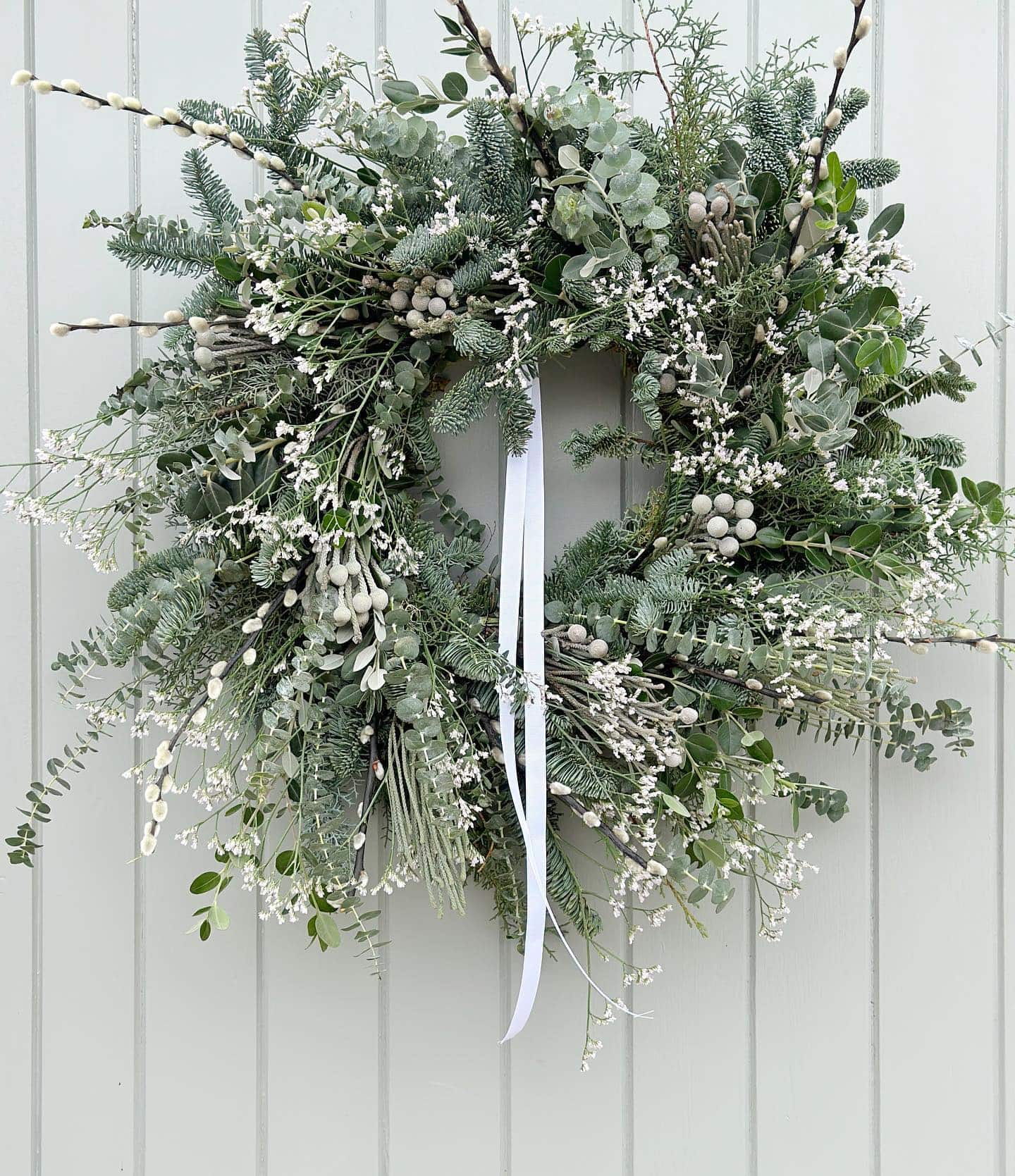 wreath idea featuring greenery, blue ribbon and baby's breath flower