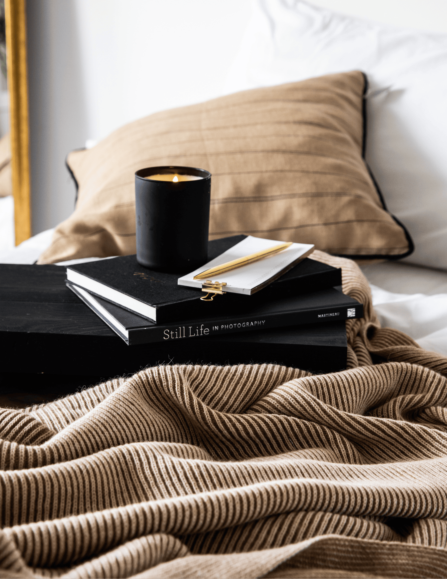 coffee cup on top of books on bed for a Winter self-care routines and practices blog post