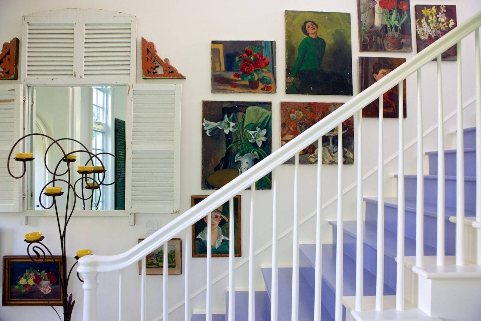 Entryway in beach english cottage style featuring stairs with blue rag and impressionist art