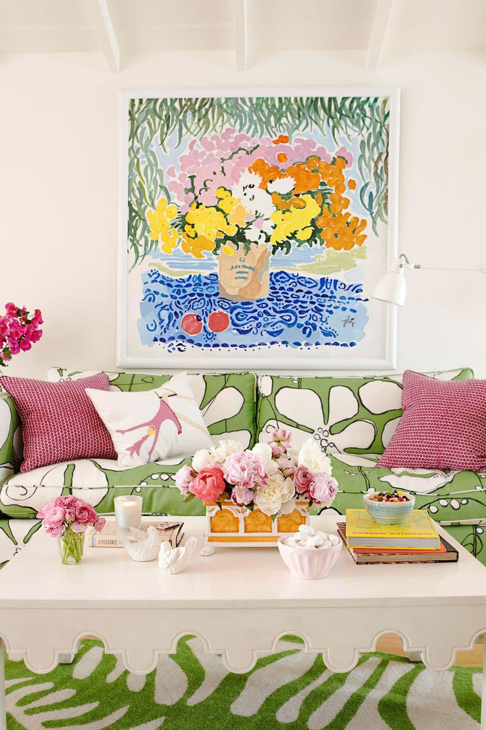 Large floral painting above a modern green couch with pink and mauve pillows featured in summer decor ideas