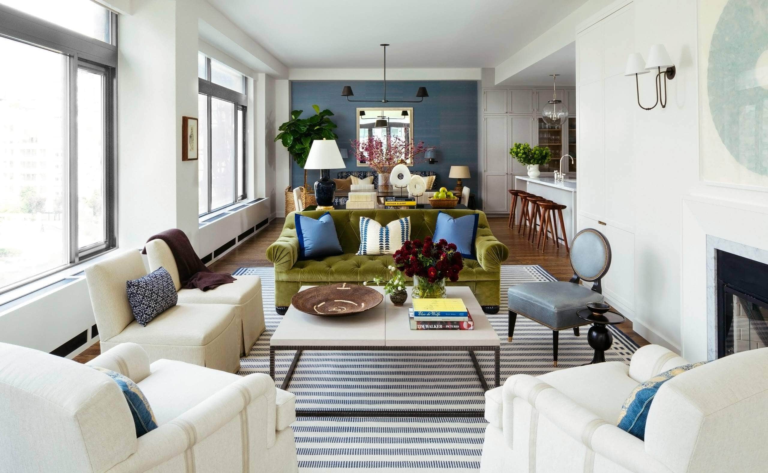 Open concept room with blue walls and large mirror. White and blue patterned sofa as a focal point, accented by mustard and white throw pillows. Transitional aesthetic with sophisticated ambiance.