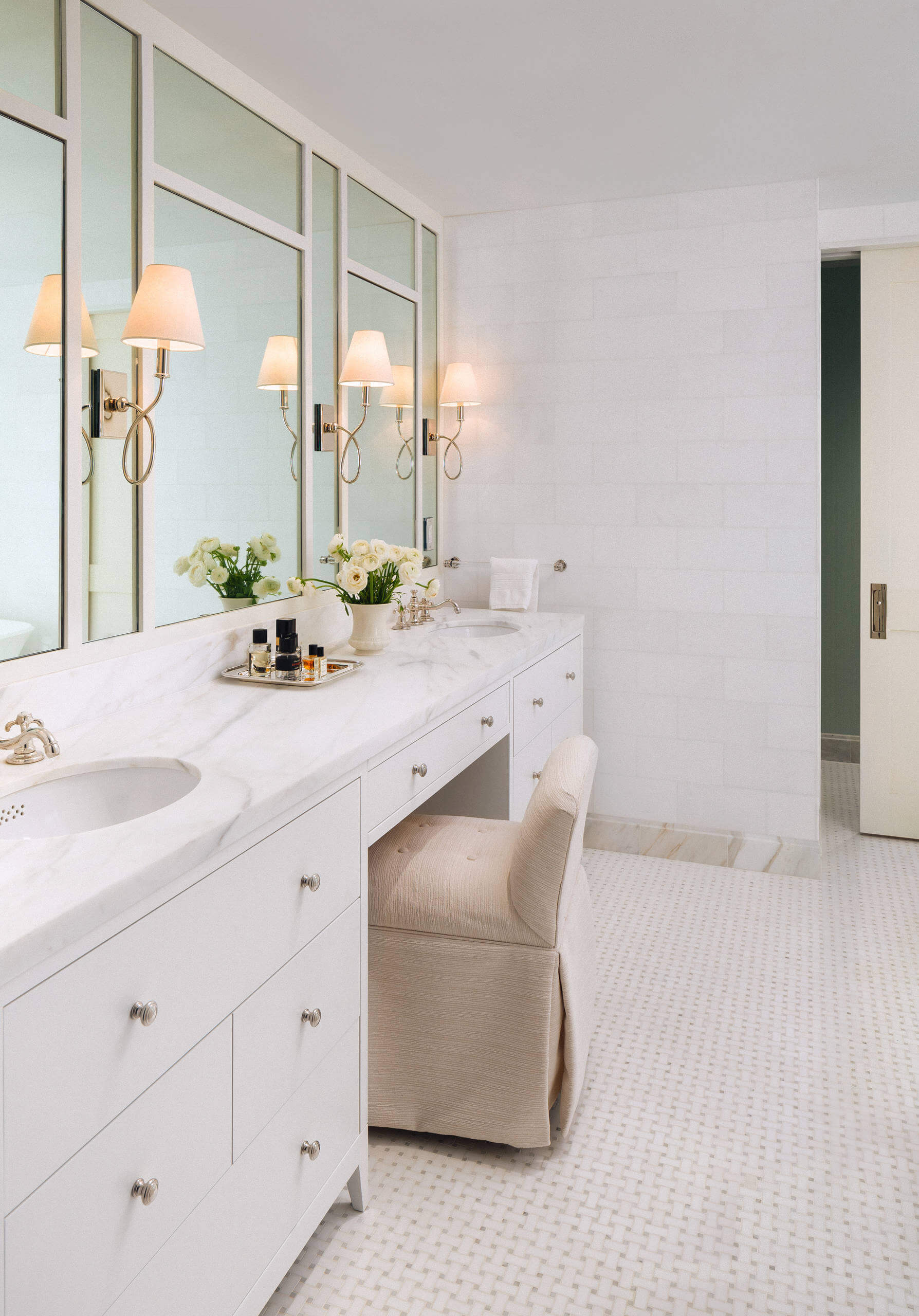 Spa-like bathroom with white walls and sage green details. An expansive vanity topped with marble is the main focal point, accented by wall mirrors. Transitional aesthetic with sophisticated ambiance.