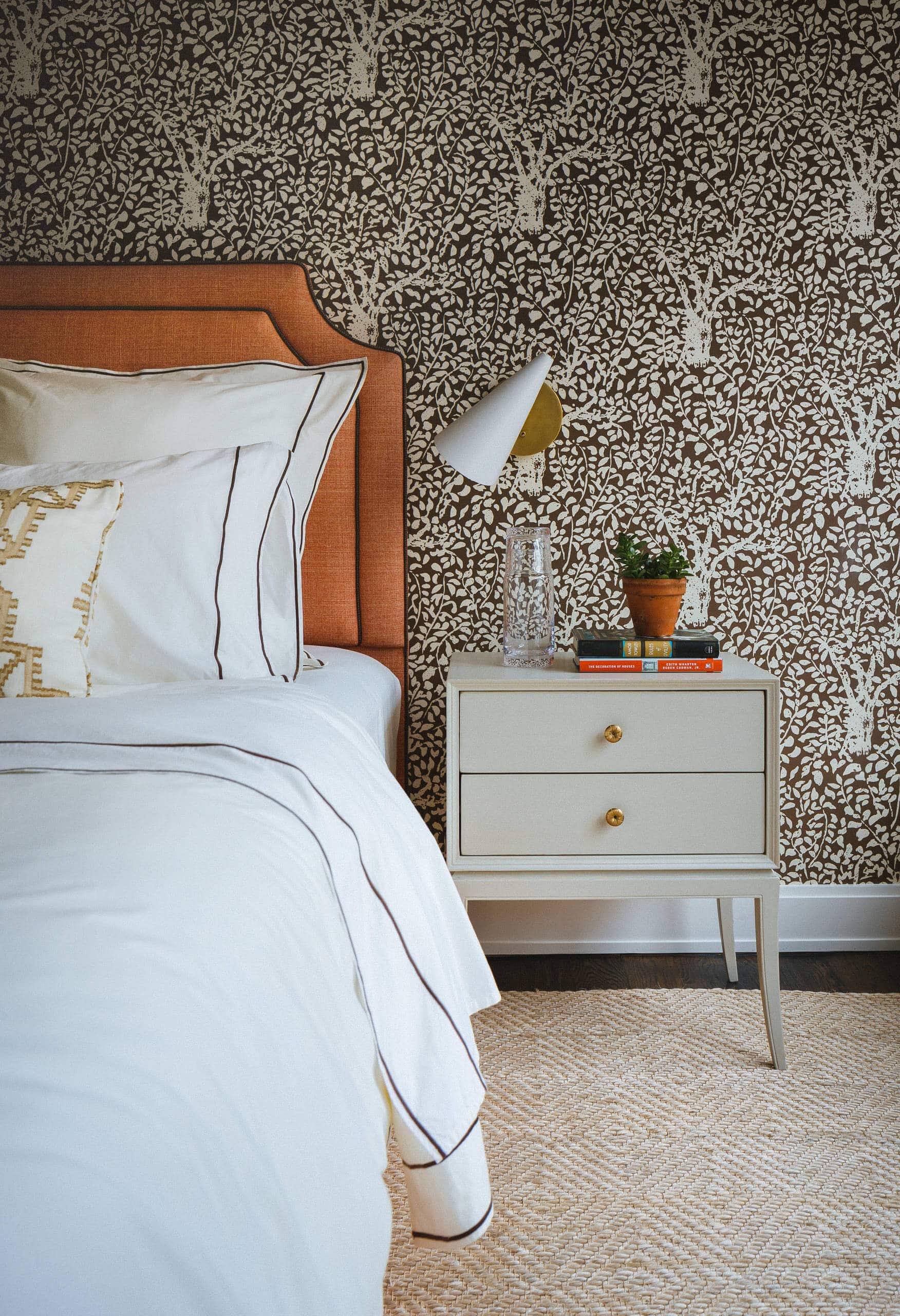 Chic bedroom with serene aqua walls. Large bed and ivory rugs work as the focal points, accented by a patterned armchair. Transitional aesthetic with sophisticated ambiance.