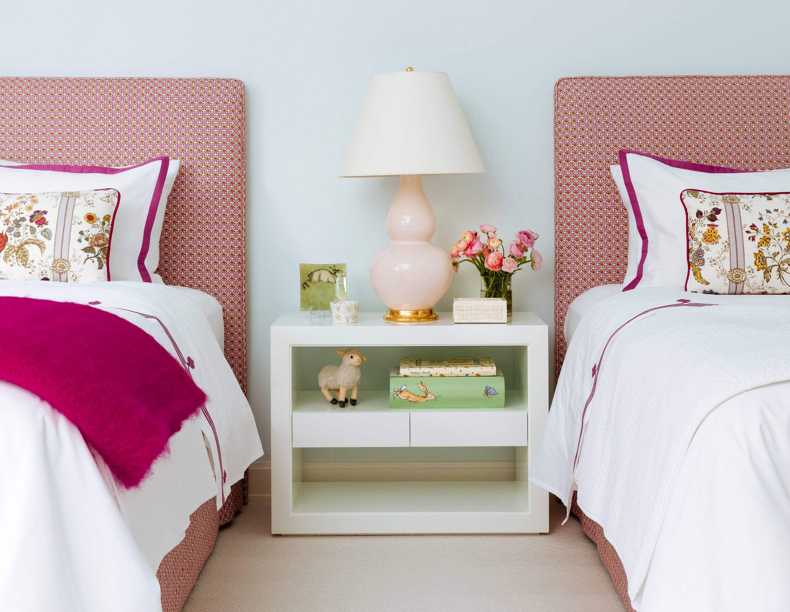 Mid-sized transitional kids' room featuring twin beds, with light blue walls and hot pink decor accents.Transitional aesthetic with vibrant pops of color.