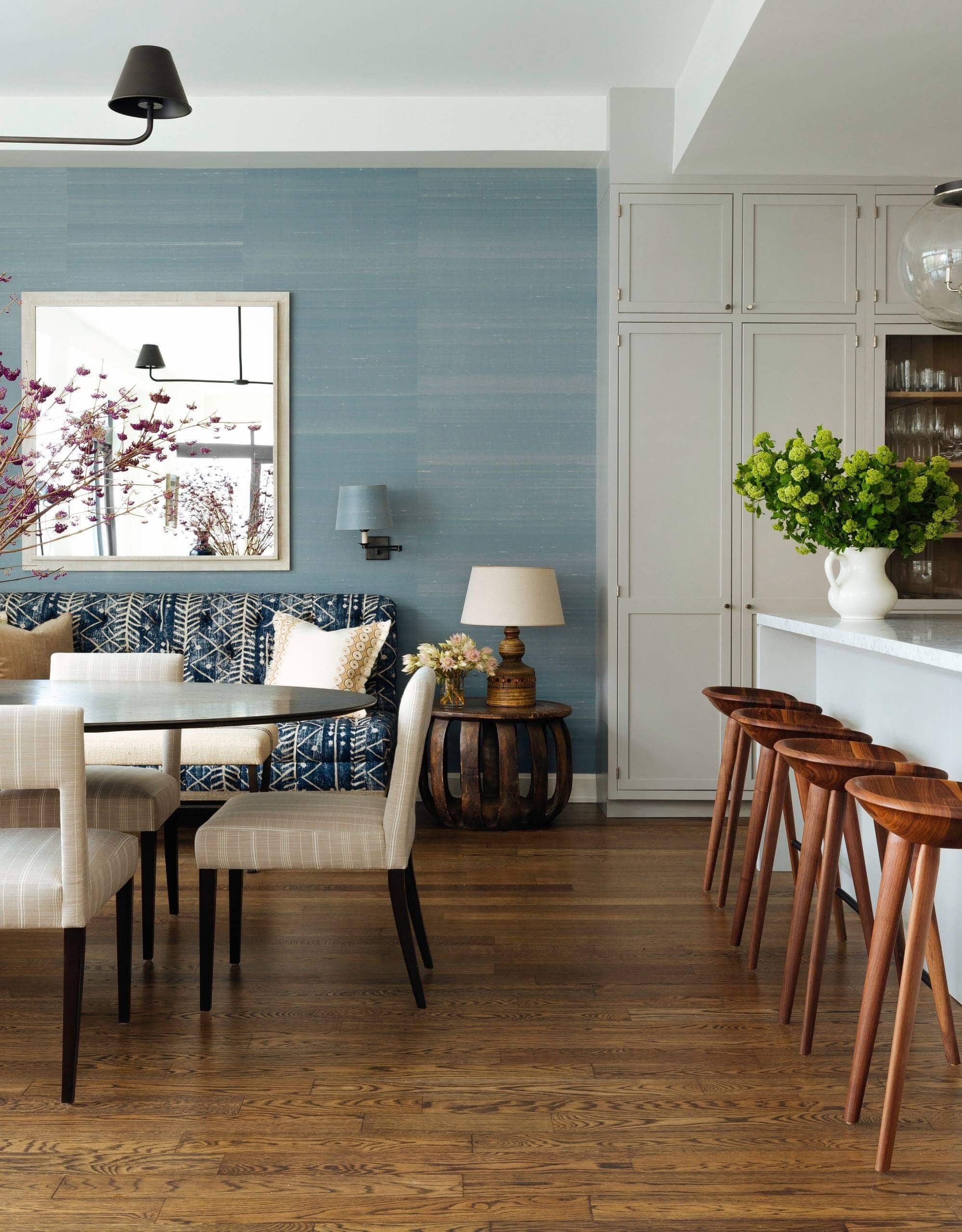 Open concept room with blue walls and large mirror. White and blue patterned sofa as a focal point, accented by mustard and white throw pillows. Transitional aesthetic with sophisticated ambiance.