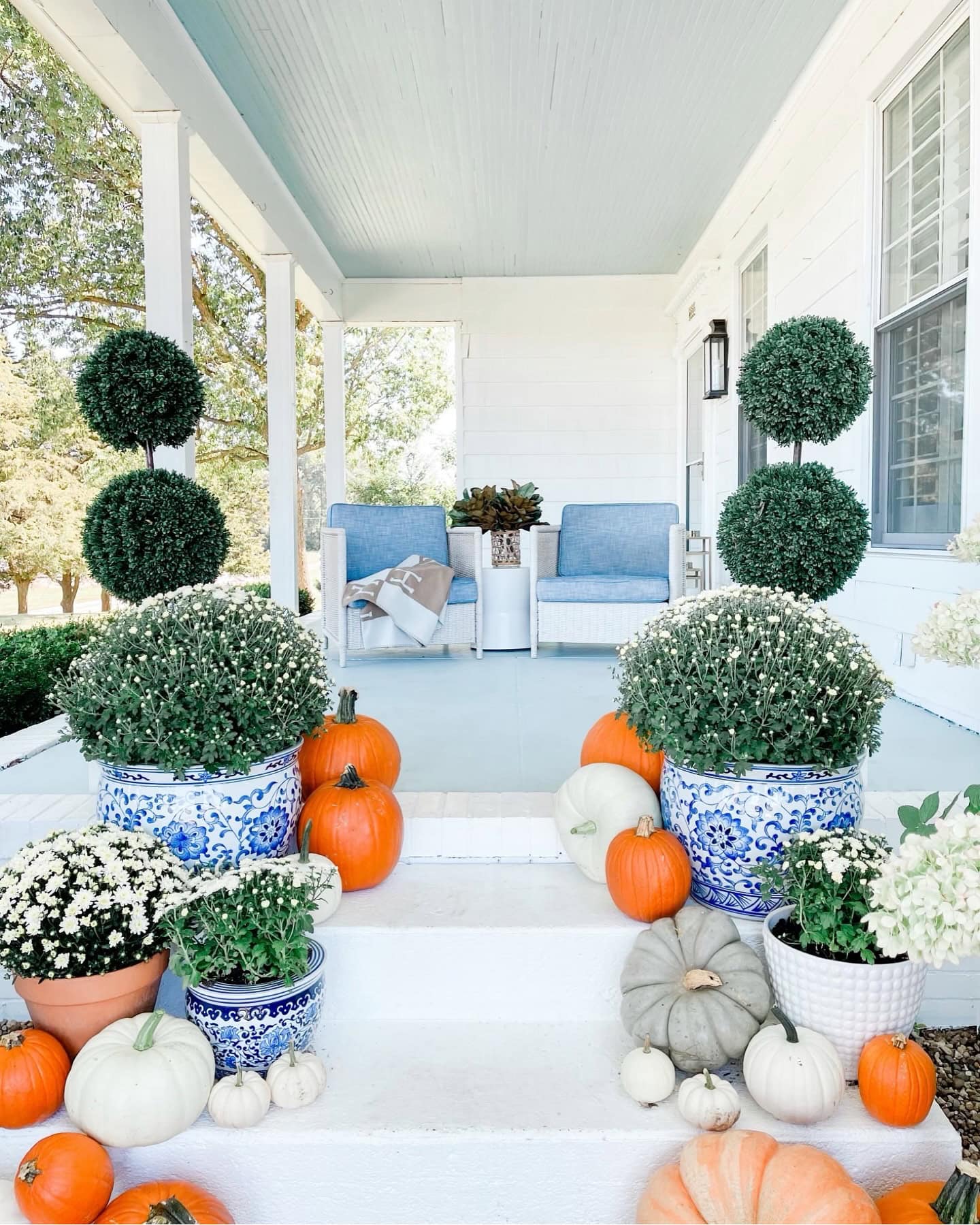 Example of fall porch decorations featuring a traditional white and blue front door porch