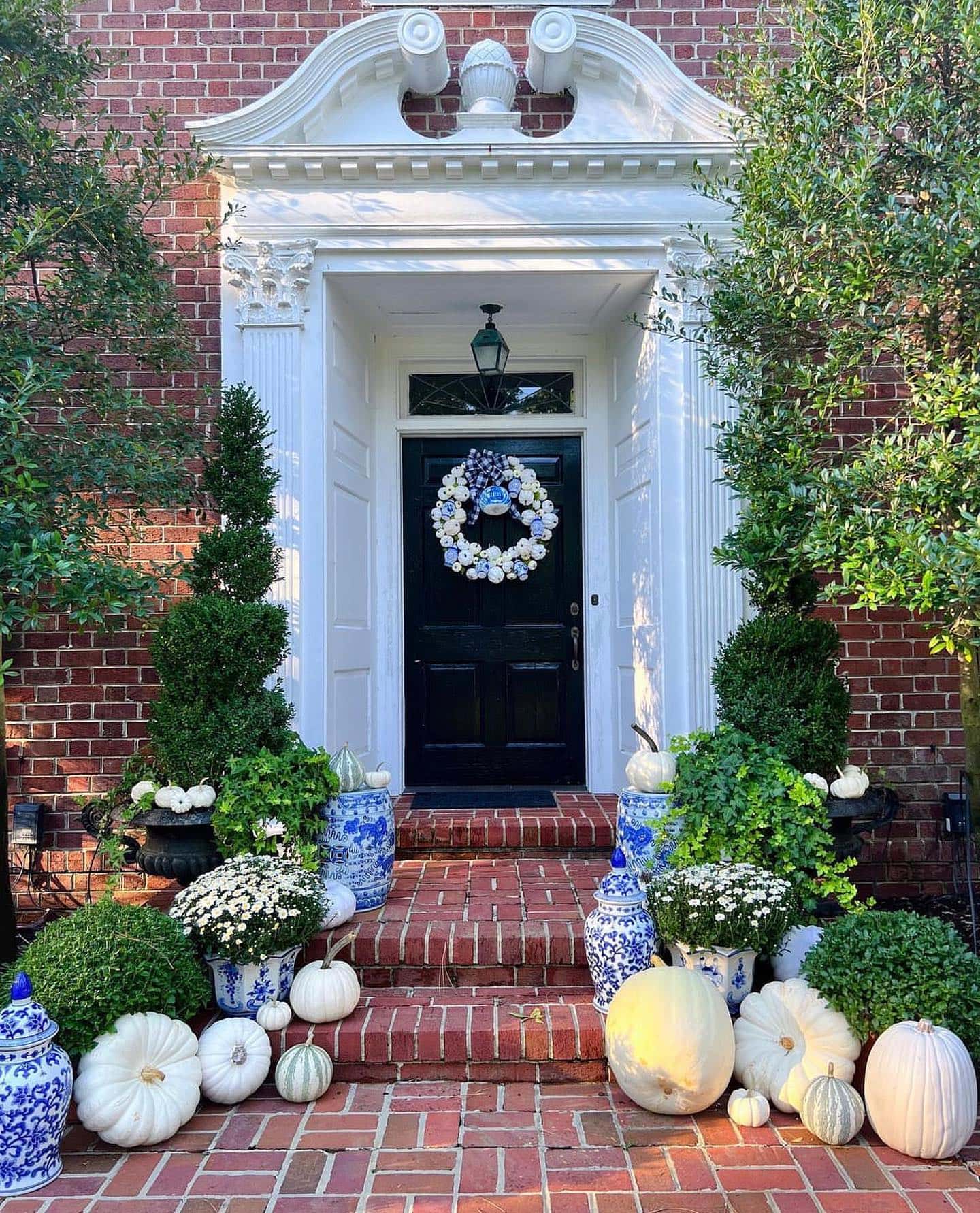 Example of fall porch decorations featuring a traditional white and blue front door porch