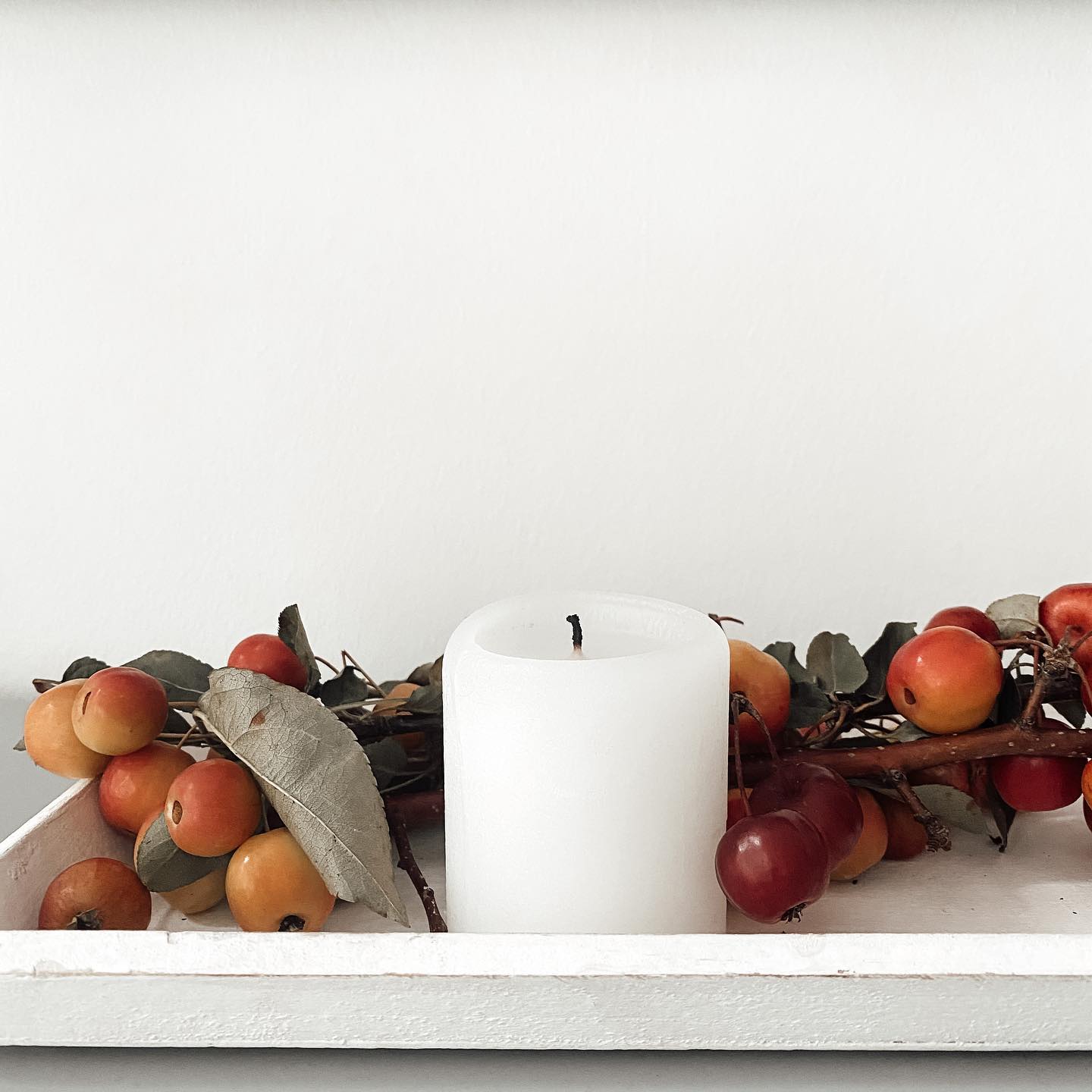 Example of minimalist fall decor ideas featuring a candle arrangement with seasonal fruit