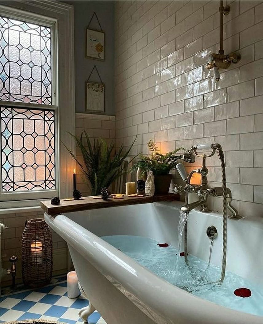 Fall bathroom decor idea featuring cozy bathtub with lit candles and plants