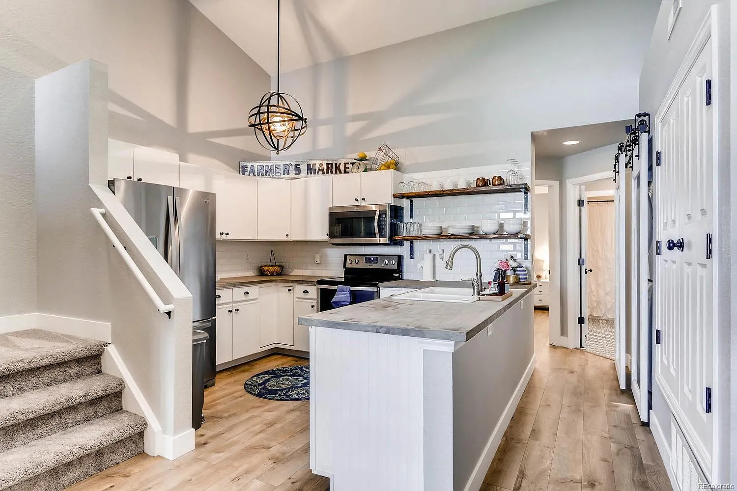 Renovated kitchen featuring white painted cabinets, subway tile backsplash, and open shelving in a Colorado condo.