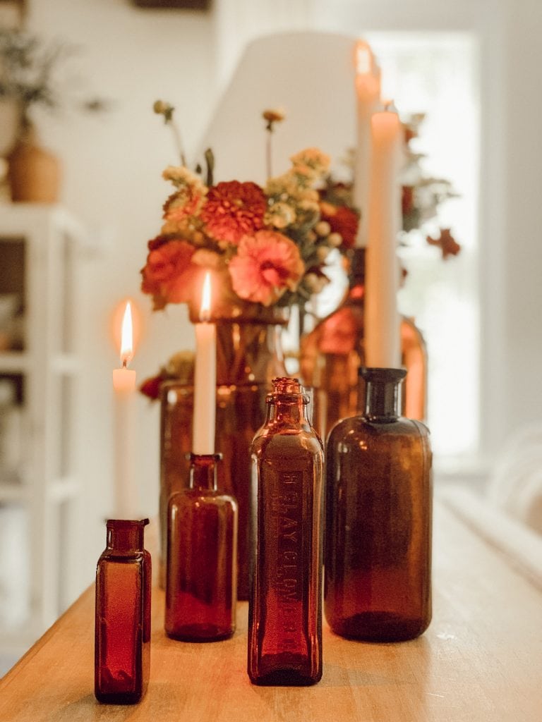 Example of minimalist fall decor ideas featuring jars and bottles in amber with candles and flowers