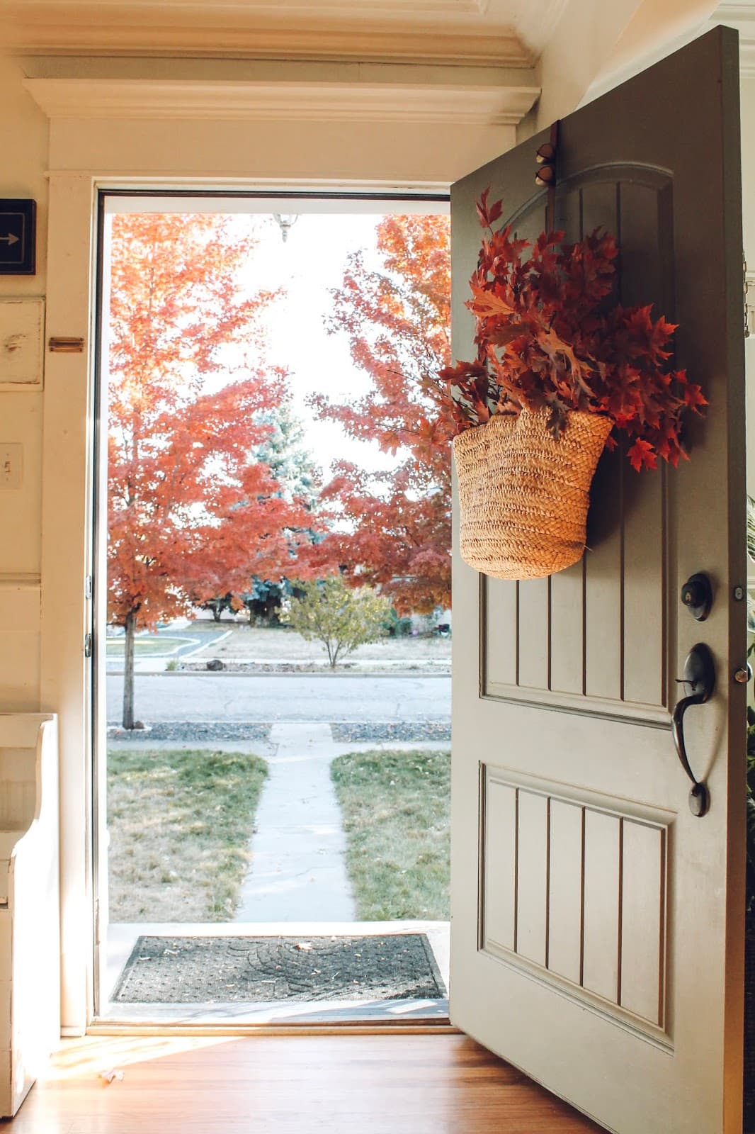 Example of minimalist fall decor ideas featuring front door with basket filled with branches and flowers