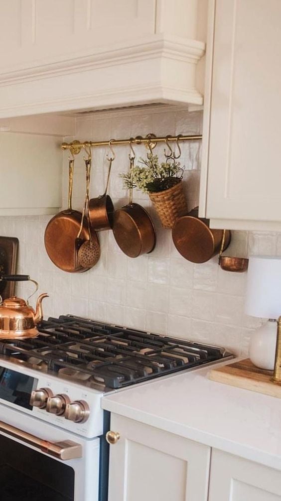 Example of minimalist fall decor ideas featuring kitchen rack in solid brass with hanging pots and pans