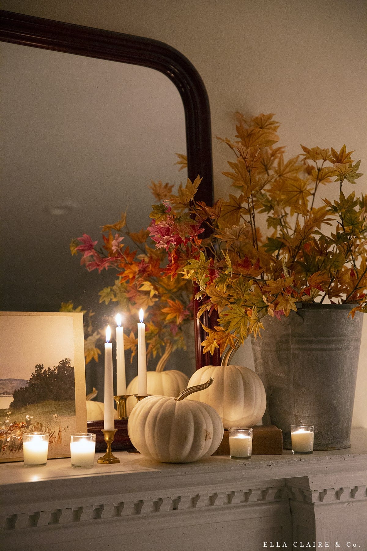 Example of minimalist fall decor ideas featuring fireplace mantel with candles and orange branches in vase
