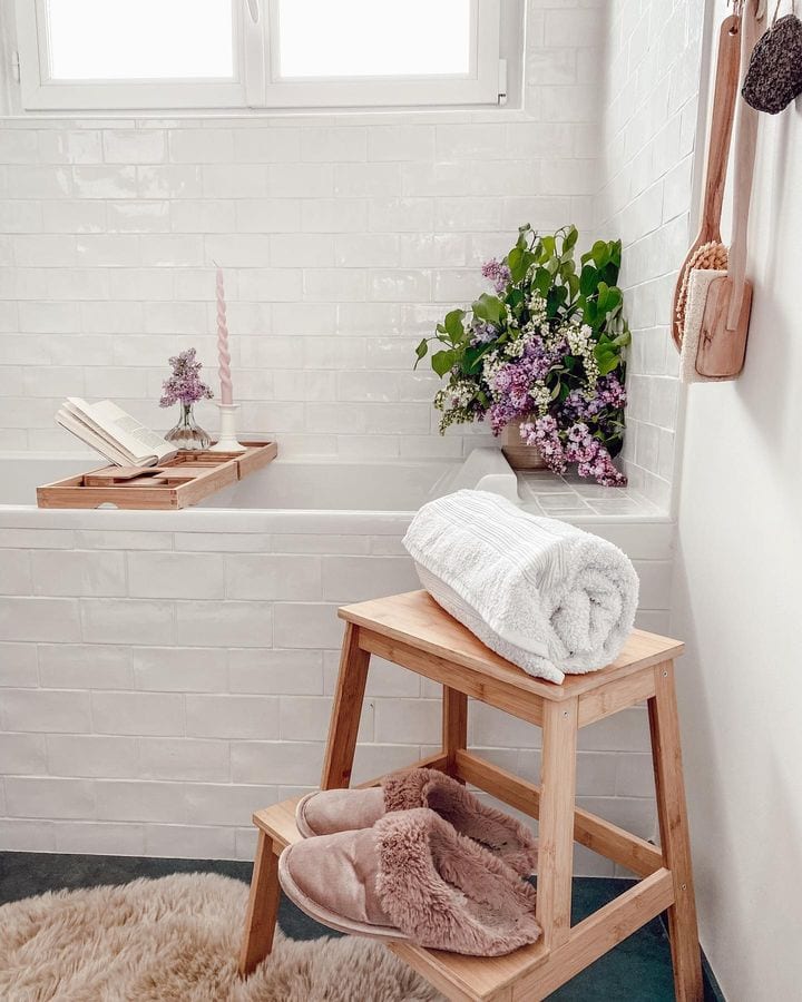 Fall bathroom decor idea featuring a simple white bathtub with a wooden step stool