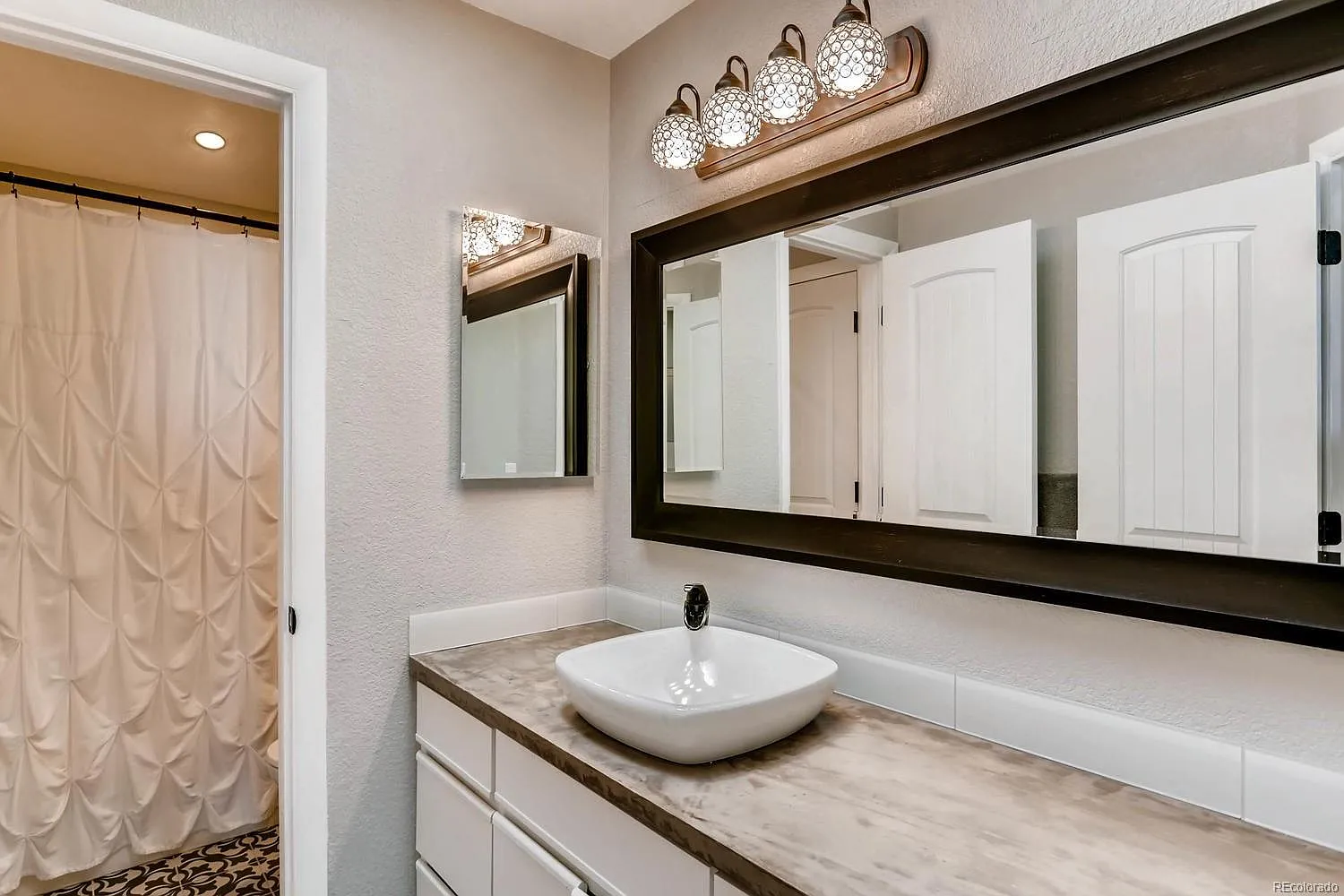 Modernized bathroom with concrete countertops, updated sink, new light fixture, and fresh flooring after DIY renovation."