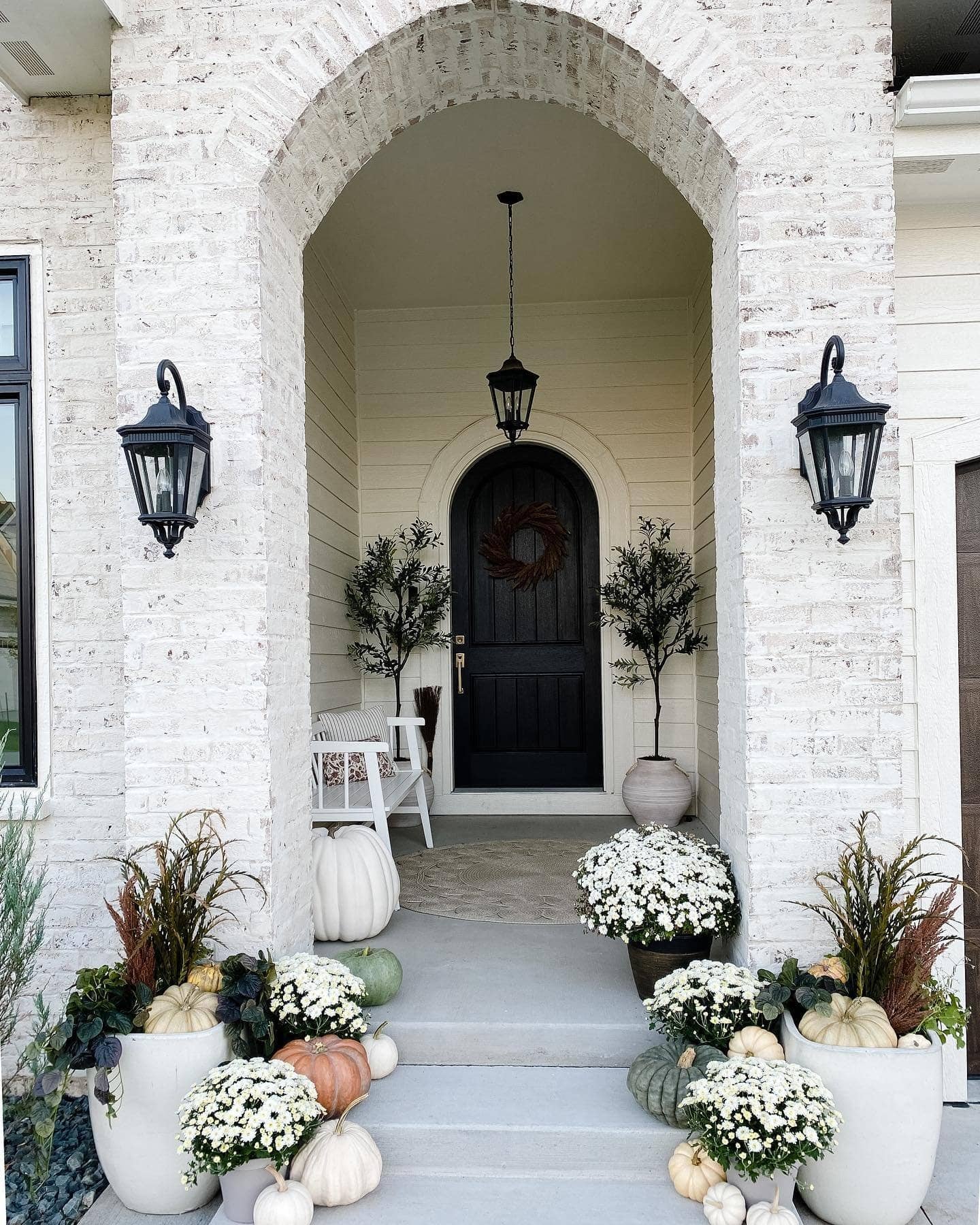 Example of fall porch decorations featuring a traditional black and white front door porch