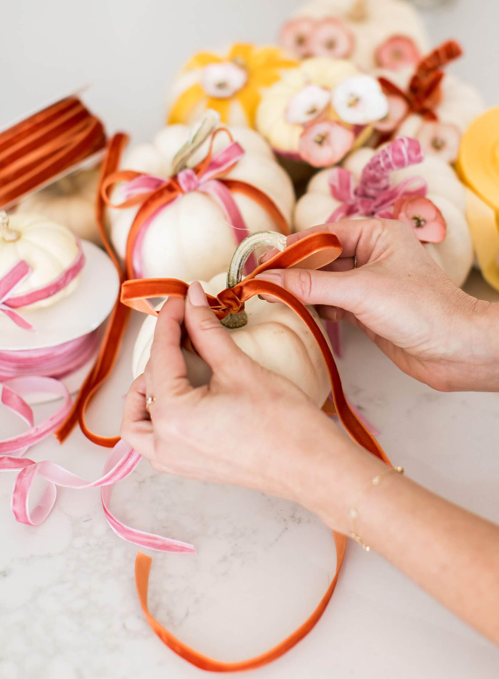 Creative no carve pumpkin decorating idea featuring ivory pumpkins with flowers and ribbons in red, pink and yellow