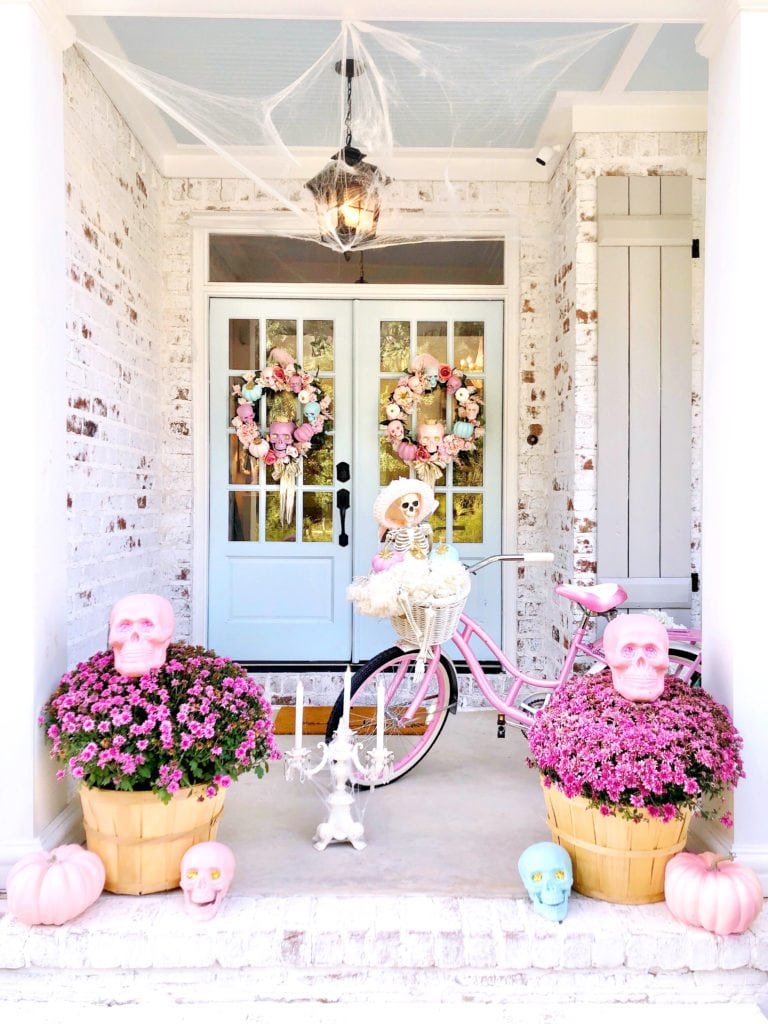 Pink Halloween decorations example featuring an entryway with vibrant pink decor and skeleton in a bicycle