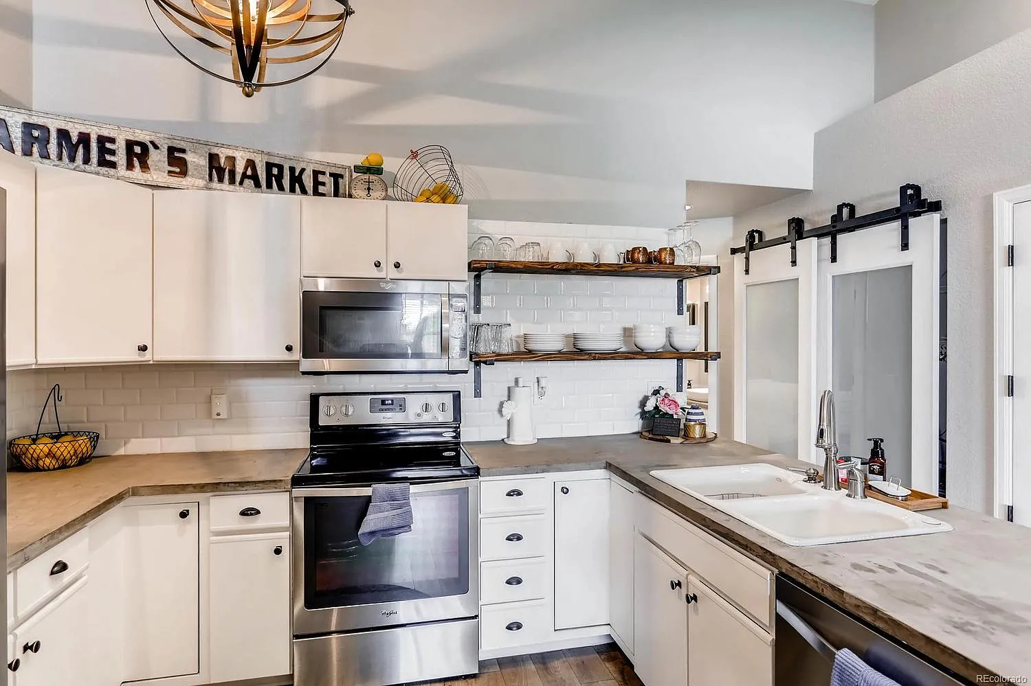 Renovated kitchen featuring white painted cabinets, subway tile backsplash, and open shelving in a Colorado condo.