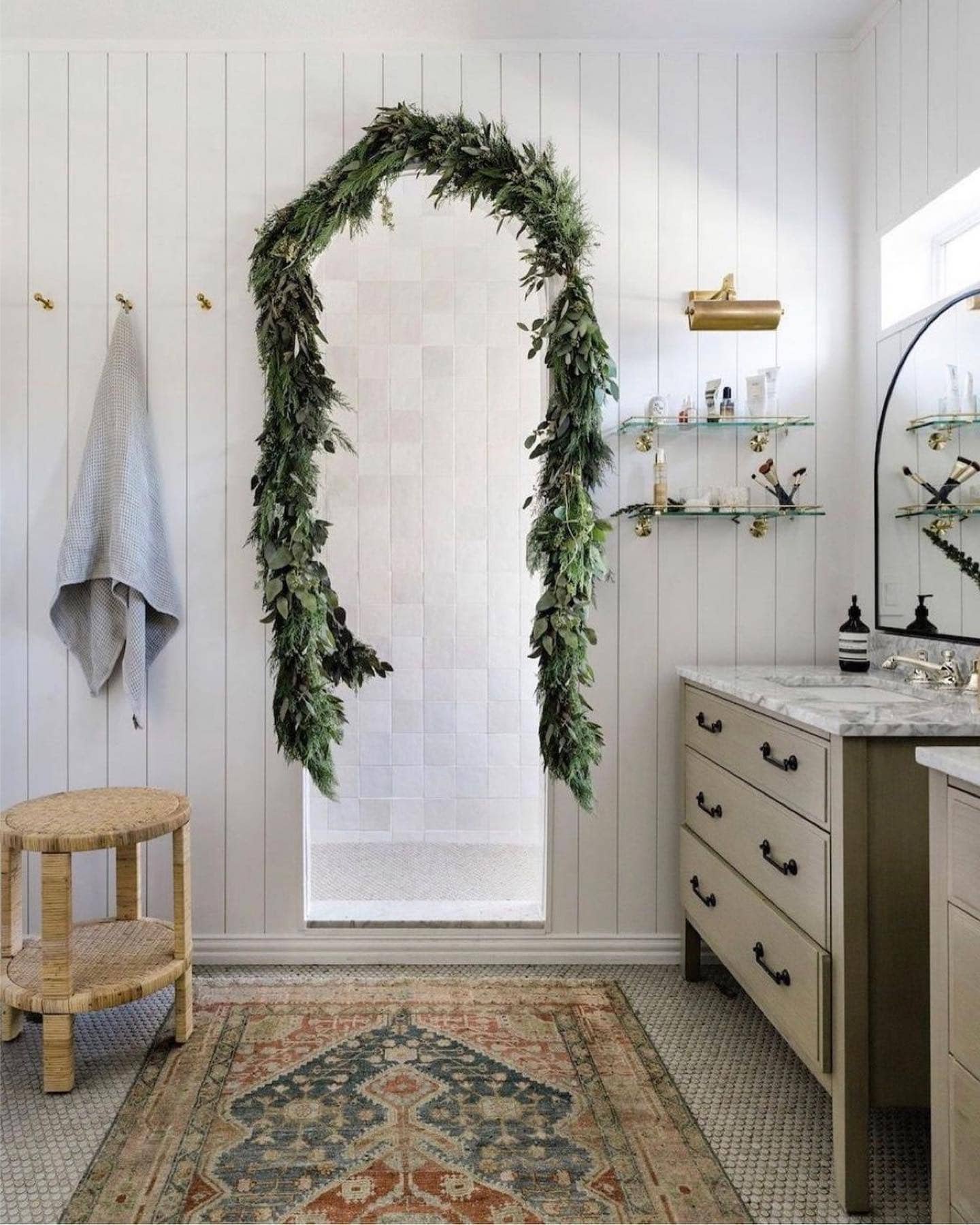 Ideas and tips for Christmas bathroom decor featuring a bathroom with modern style, showcasing arched door wrapped with a garland.
