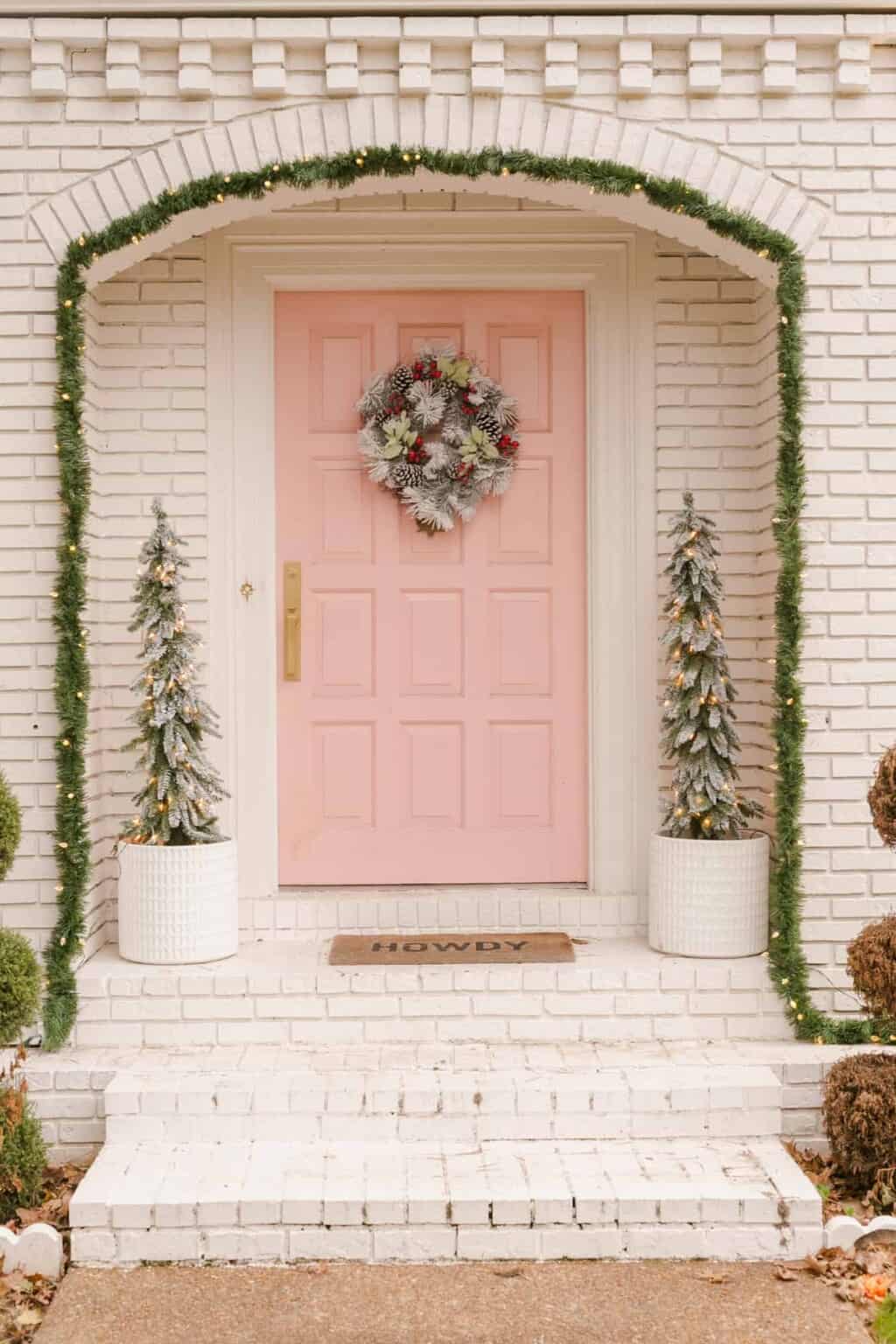 Create magical Christmas porch decor with these ideas example featuring a pale pink front door with Christmas decor in porch