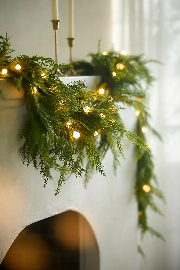Example of cozy Christmas decor featuring living room decorated with garland in modern heritage style.