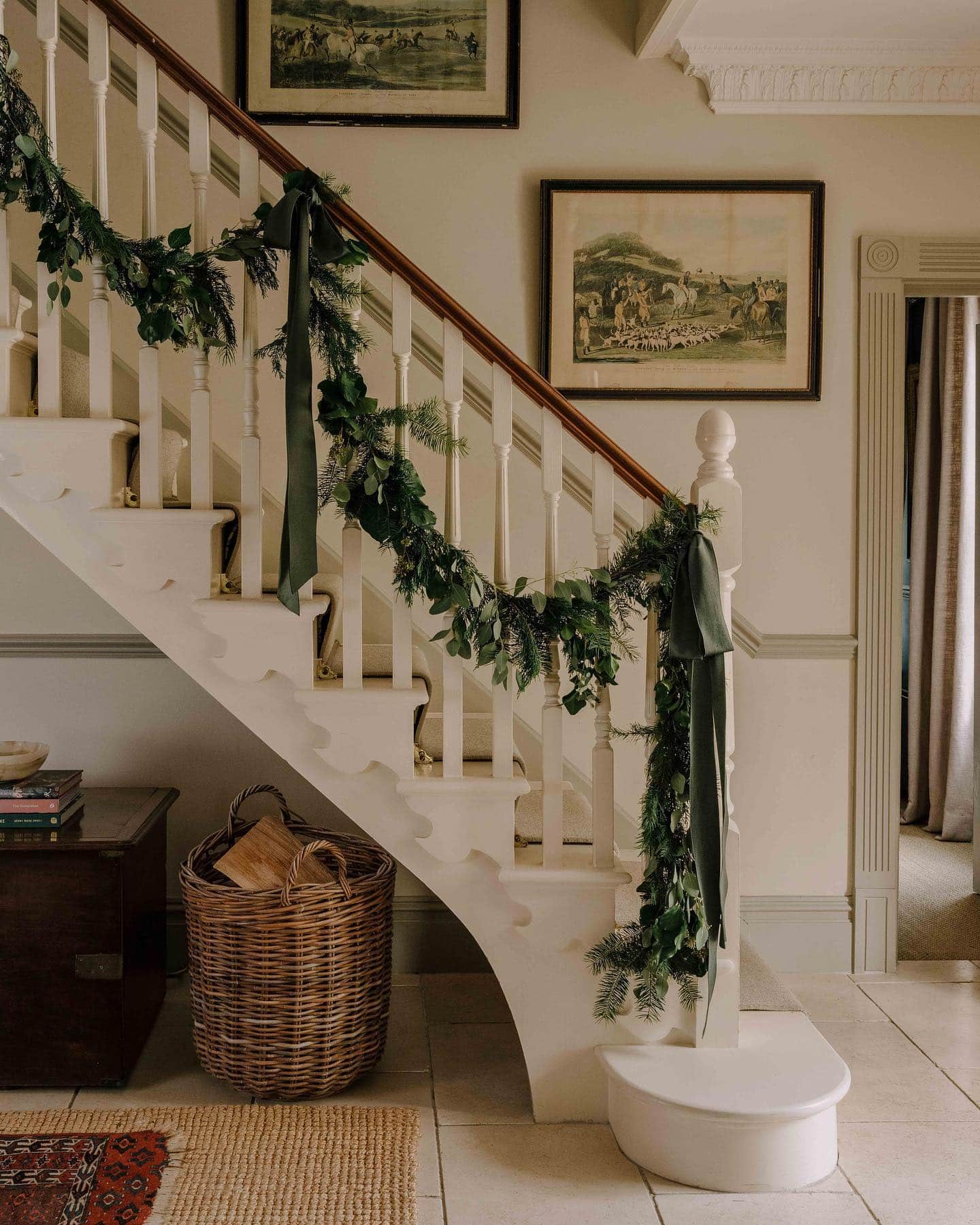 Christmas staircase decor idea featuring a green garland and velvet ribbons.
