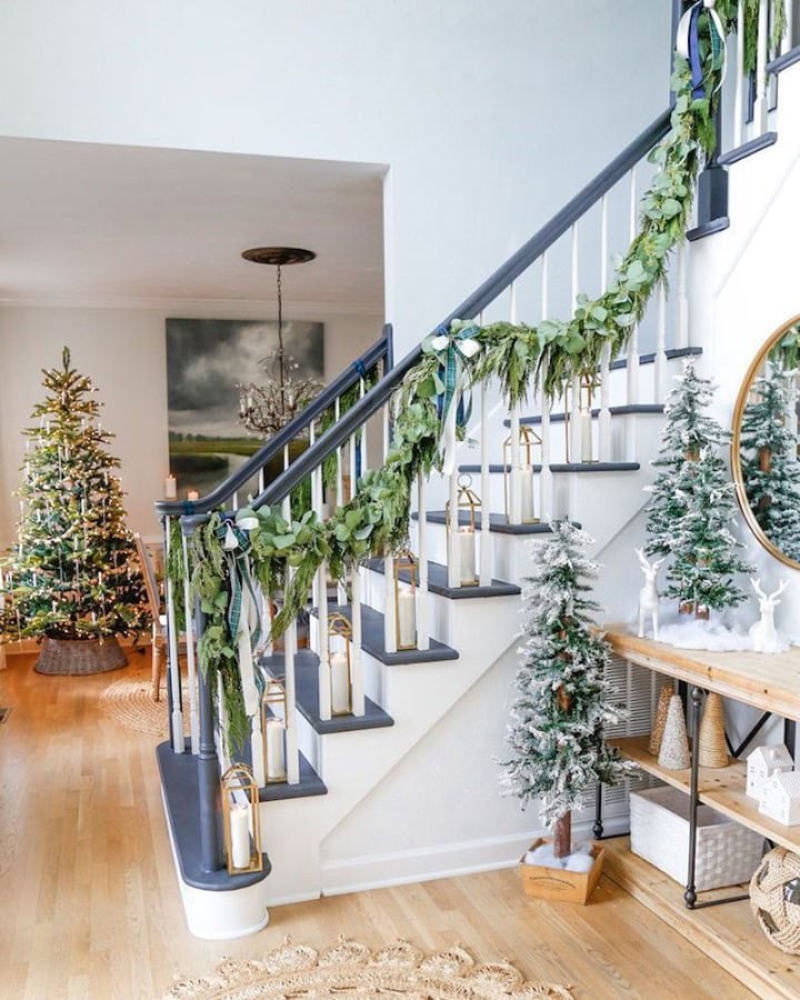 Christmas staircase decor idea featuring a green garland and powdery blue bows.