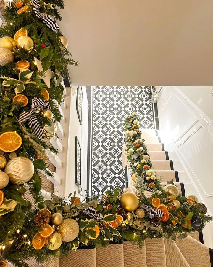 Christmas staircase decor idea featuring a staircase with garlands featuring drid oranges