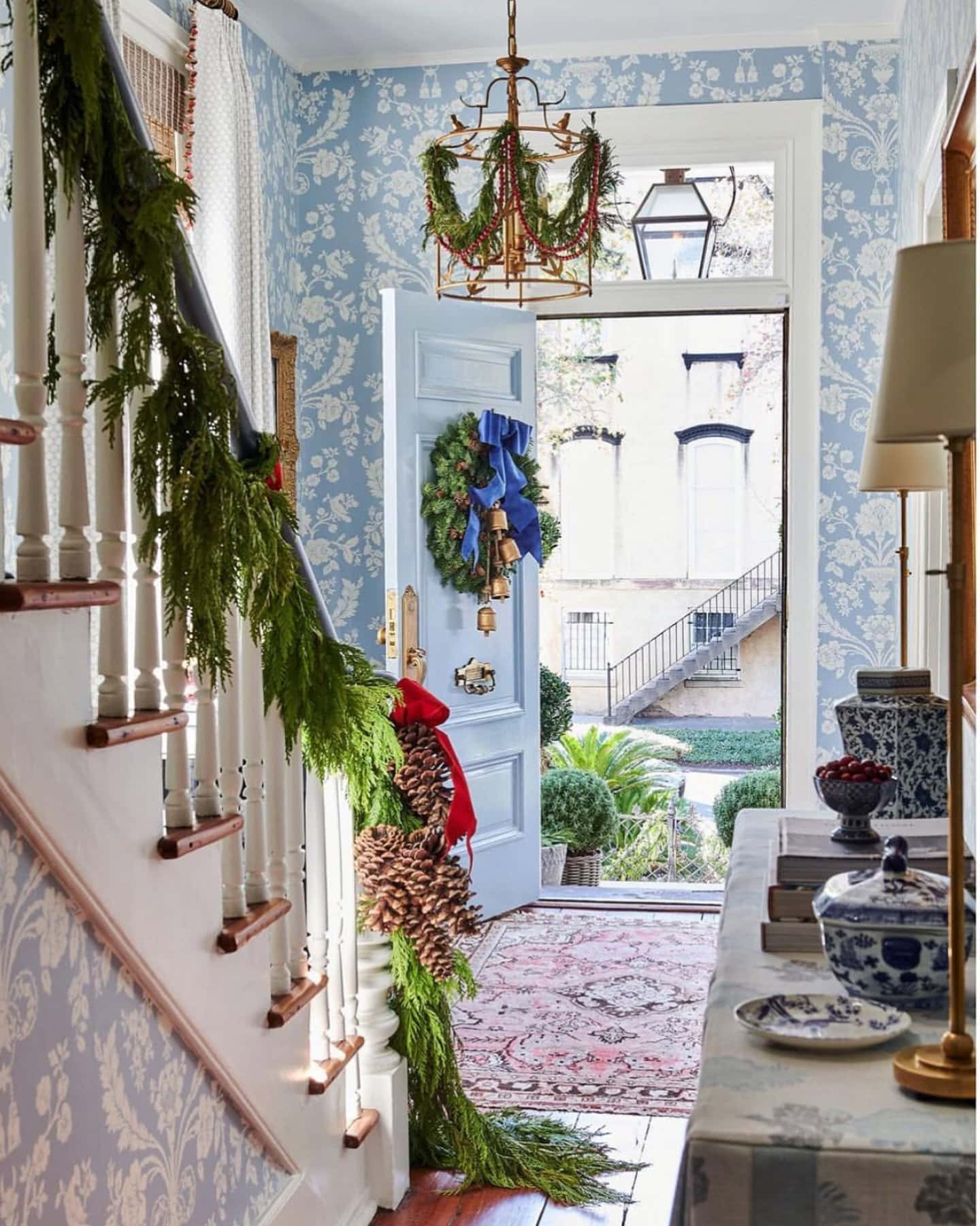 Christmas staircase decor idea featuring a green garland and red bows.