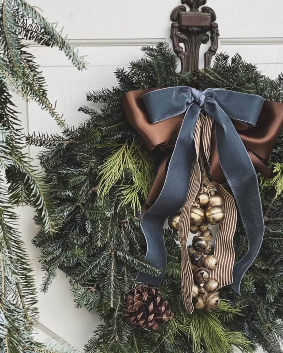 front door styled for Christmas with a large wreath with velvet bows and ribbons