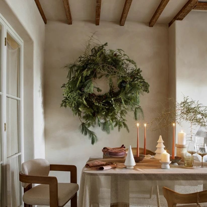Dining room styled for Christmas with natural style scandi with large wreath next to table