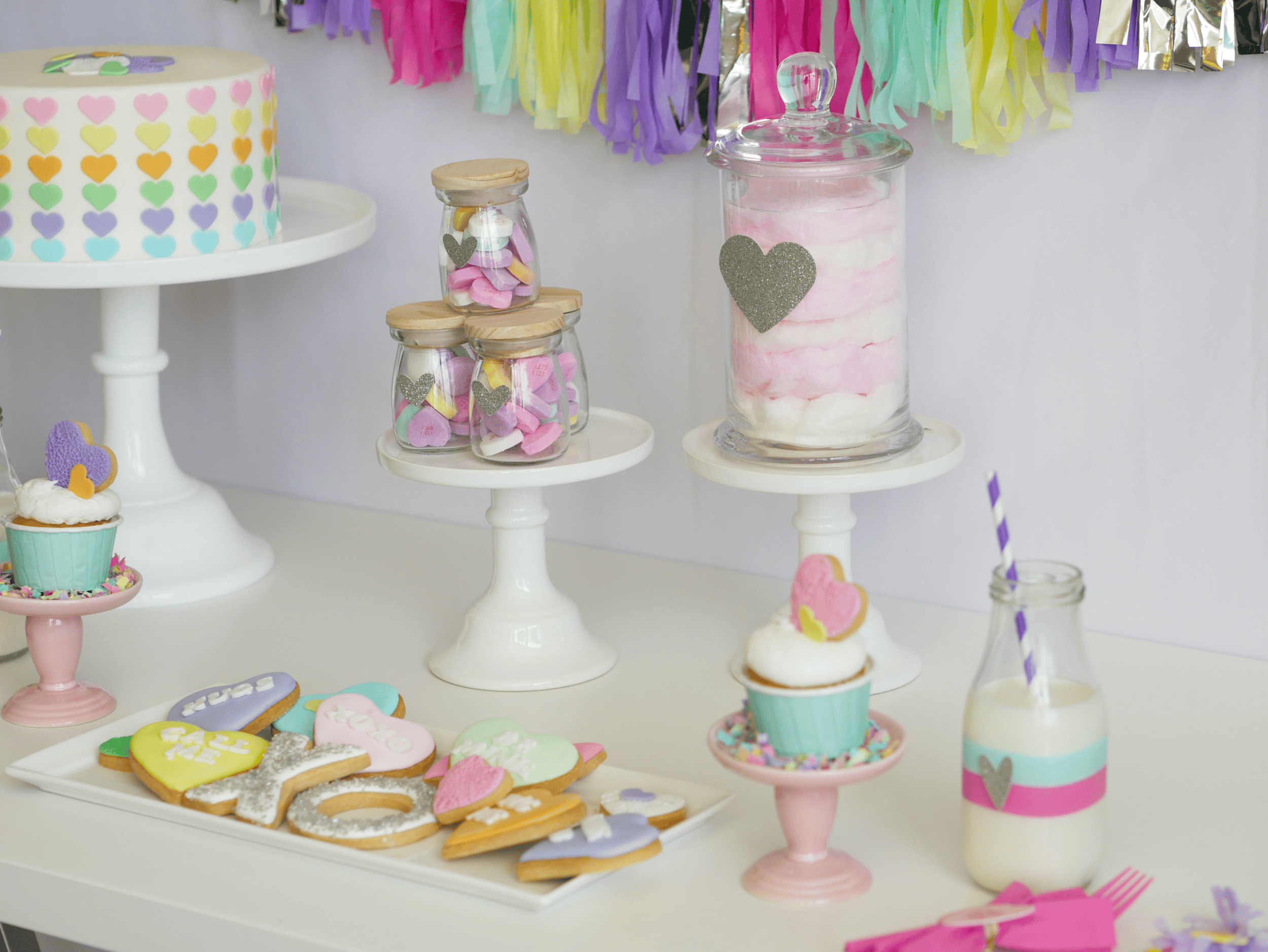 Example of Valentine’s Day kids dessert table featuring kid-friendly sweet treats in vibrant colors with on-themed decor around