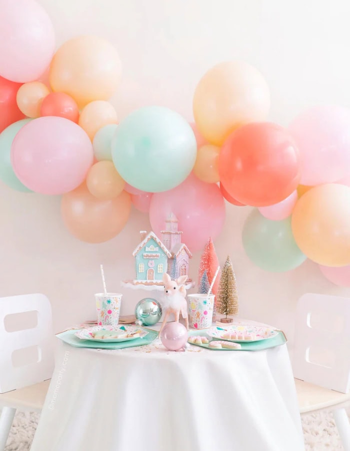 Kid-friendly Christmas party idea featuring a colorful table set up with balloons in pastel colors