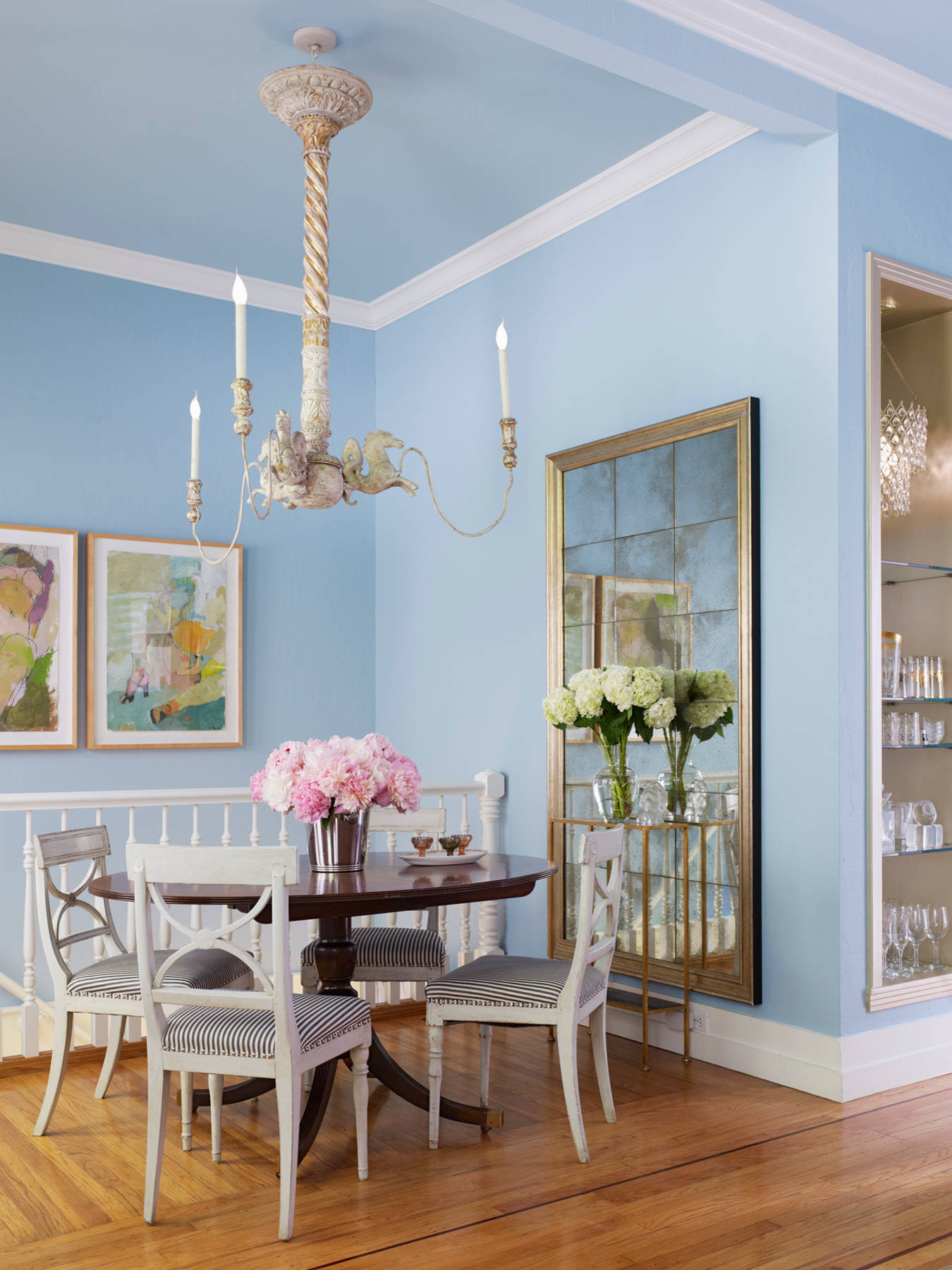Example of how to use mirrors and lighting to enhance a space featuring a dining room with large mirror in a traditional elegant style