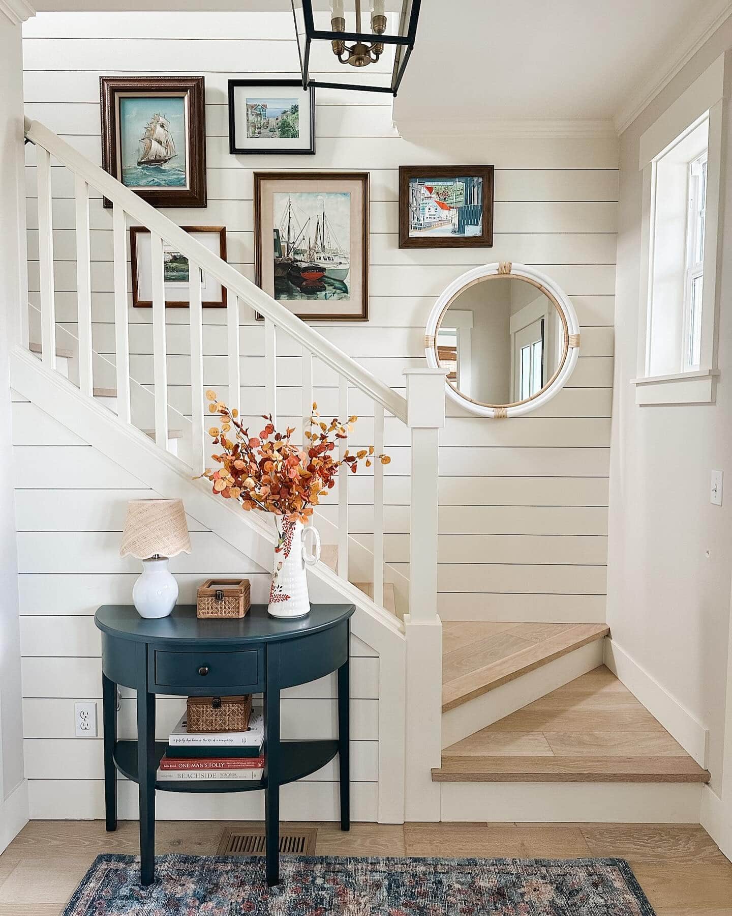 Example of how to use mirrors and lighting to enhance a space featuring a entryway with a gallery wall of mirrors in coastal style