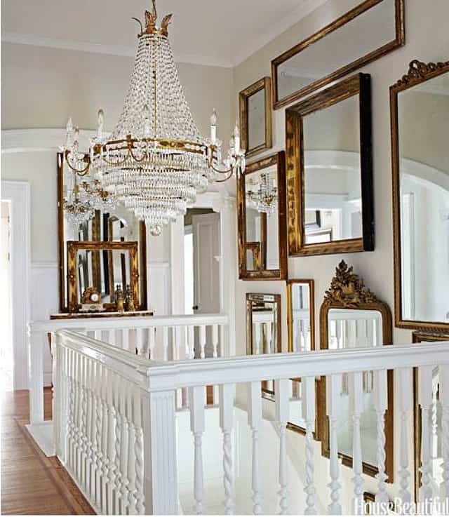 Example of how to use mirrors and lighting to enhance a space featuring a staircase with a gallery wall of mirrors in traditional home decor style