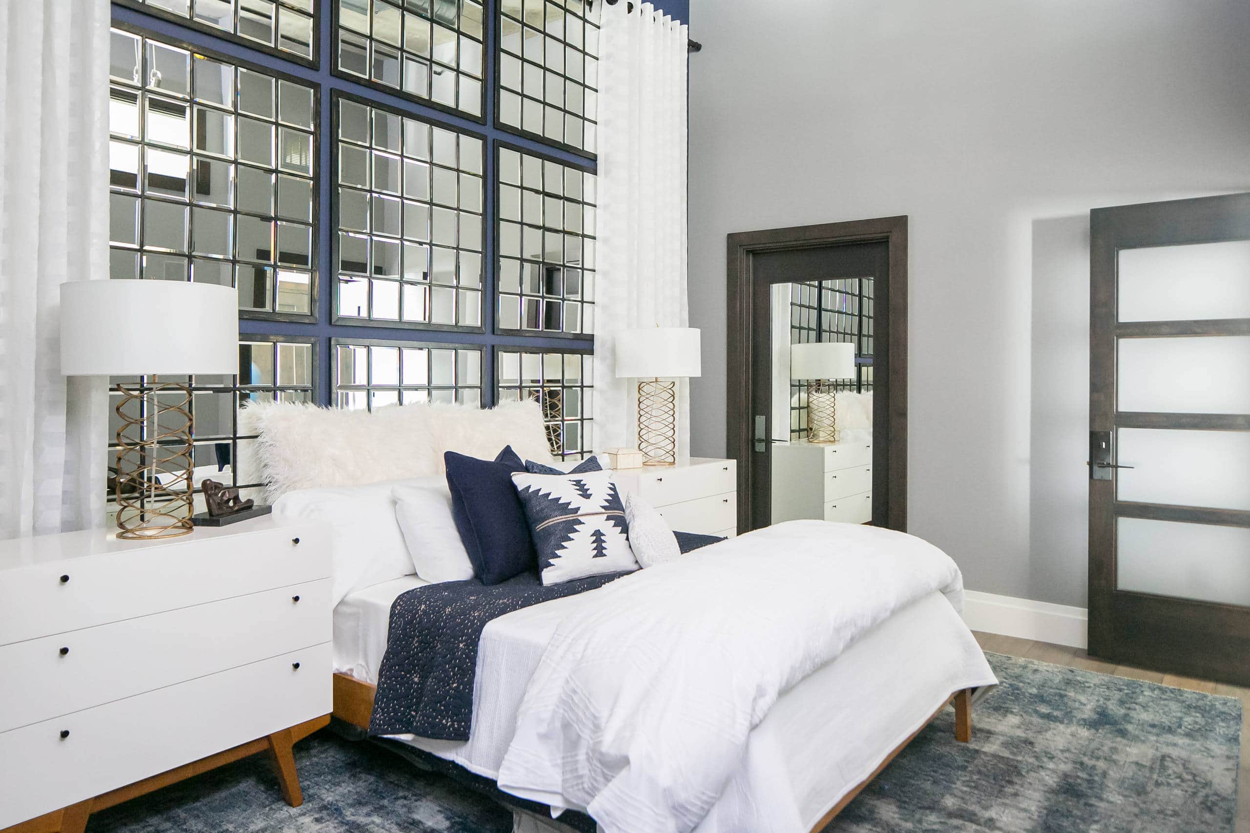 Example of how to use mirrors and lighting to enhance a space featuring a bedroom with a beveled mirror