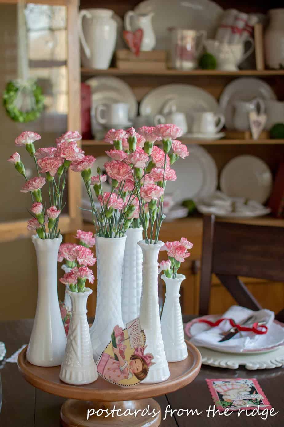 Vintage Valentine's Day decor idea featuring milk vases with pink and white floral arrangements