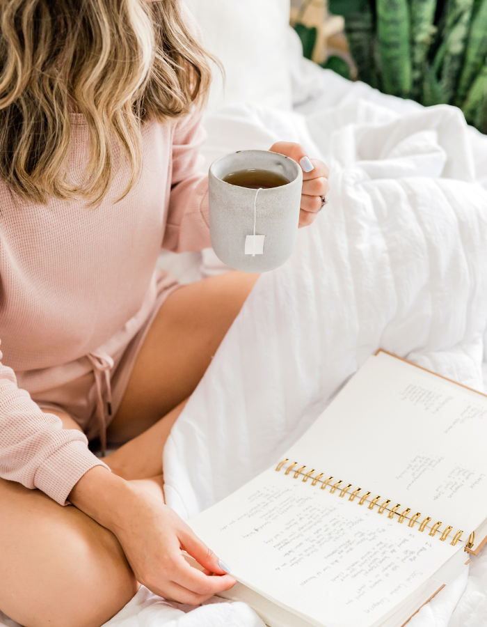 image of woman in bed enjoing coffee while reading shown as example of Valentine's day gift ideas for her