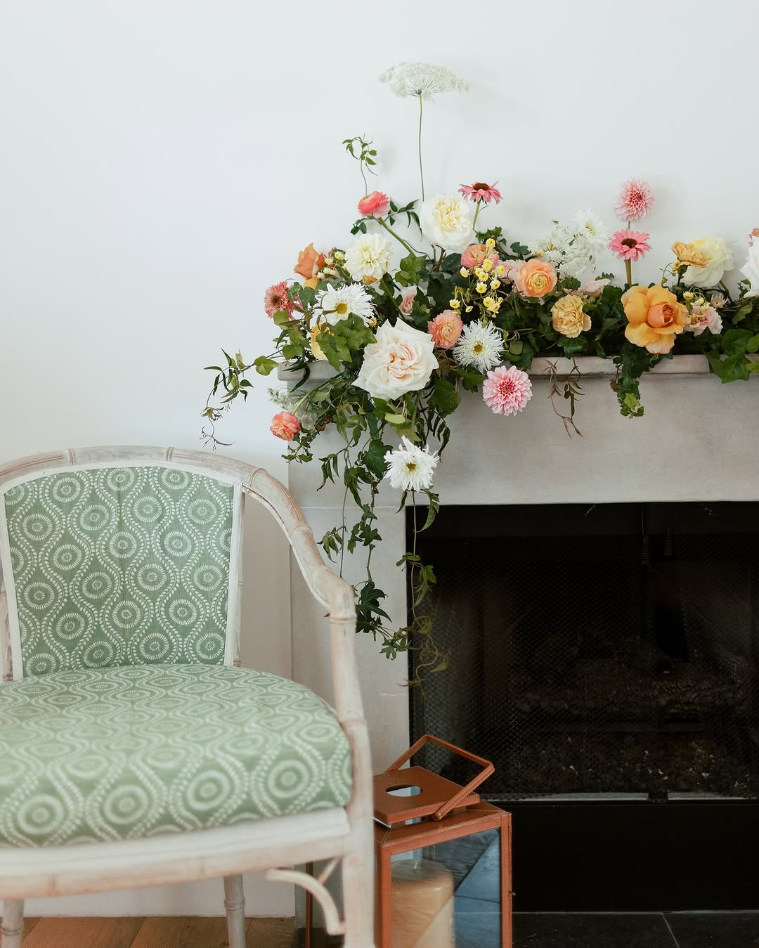 Example of transitional mantel decor style featuring a floral arrangement to one side