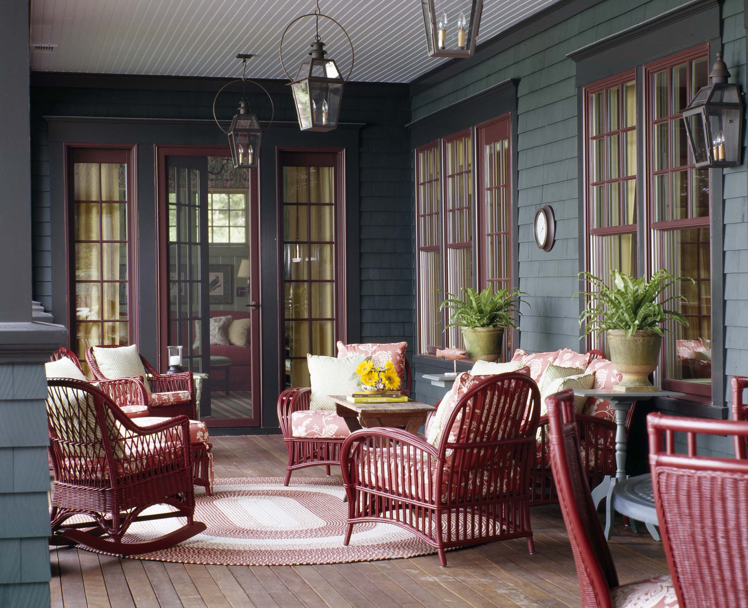 Burgundy and navy fall decorating in a porch featuring navy shiplap walls and burgundy outdoor patio sitting set