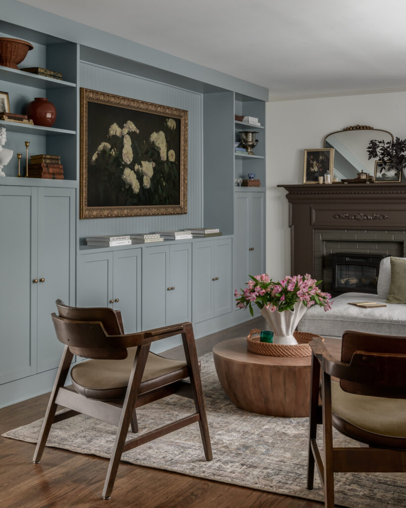 Living room with soft blue built-ins and a dark carved fireplace in a colonial home tour