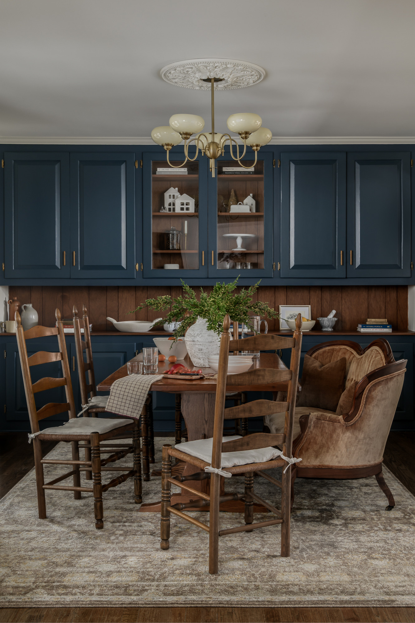 Dining room with navy cabinetry and a brass chandelier in a colonial home tour